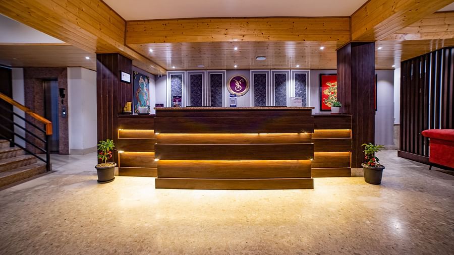 Sumitel Hotel's reception area featuring a wooden desk with warm lighting, red chairs, and decorative wall art.