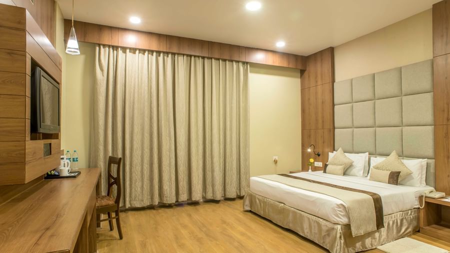 Comfortable hotel room with a double bed, a work desk, and beige curtains | The Citi Residenci Hotel Durgapur