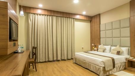 Comfortable hotel room with a double bed, a work desk, and beige curtains | The Citi Residenci Hotel Durgapur