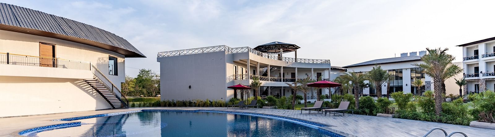 A well maintained swimming pool in front of our hotel rooms seen on a sunny day - Shervani Pebbles & Pines, Corbett