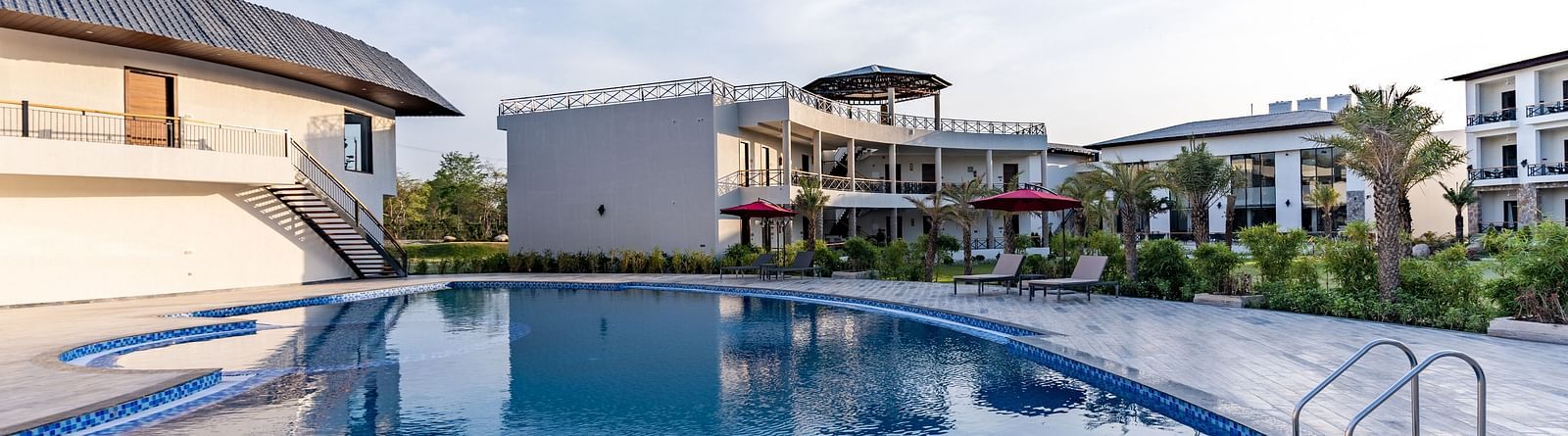 A well maintained swimming pool in front of our hotel rooms seen on a sunny day - Shervani Pebbles & Pines, Corbett