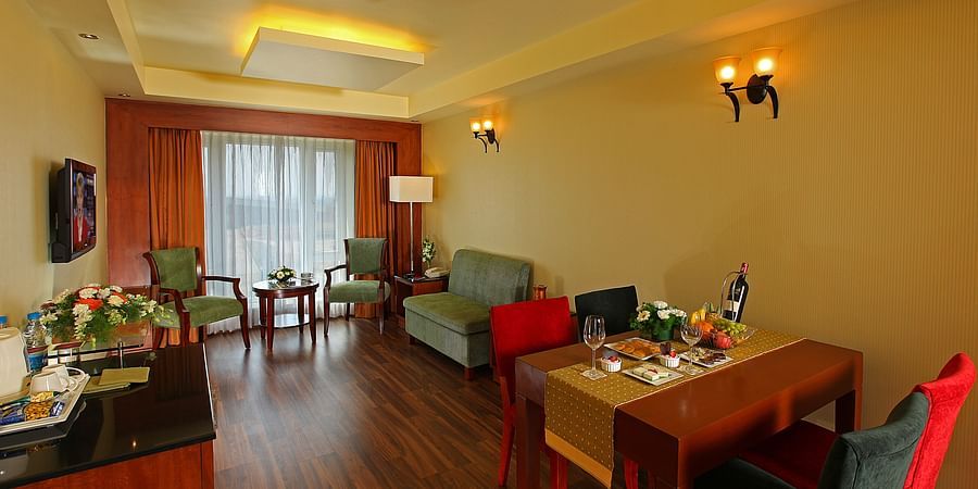 A well-lit living area with elegant seating, a dining table, and modern décor, creating a cosy and inviting ambiance. - La Classic, Hosur Road