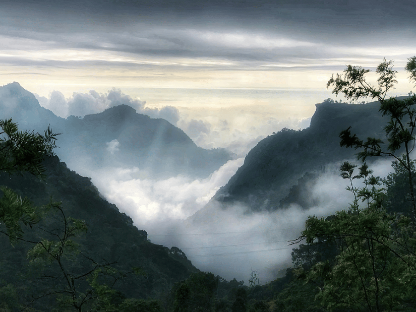 A wide-angle shot featuring mountains with a dense layer of clouds covering them.
