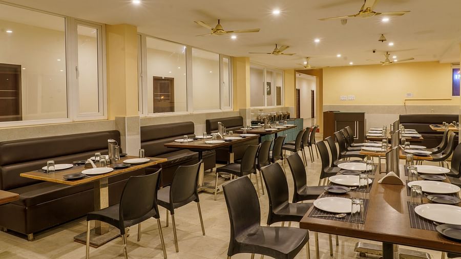 Dining area at Wyt Hotels Rameswaram featuring chairs and table with cutlery set. On the ceiling there are fans and lights.