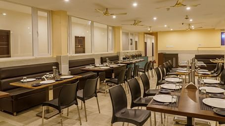 Dining area at Wyt Hotels Rameswaram featuring chairs and table with cutlery set. On the ceiling there are fans and lights.