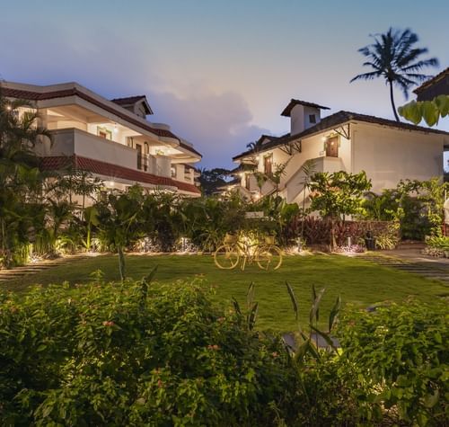 The exterior view of Heritage Village Resorts & Spa, Goa with decorative lights and trees.