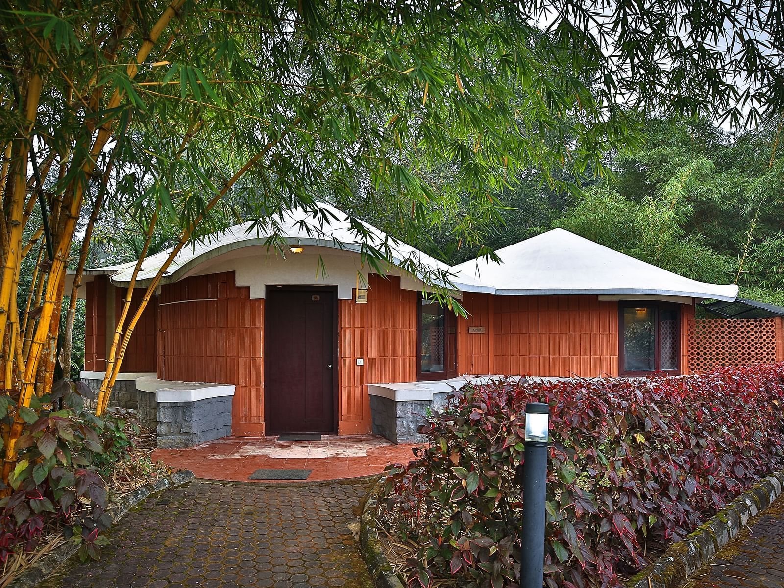a pathway with bushes on both sides leading to a cottage - Kadkani River Resort, Coorg