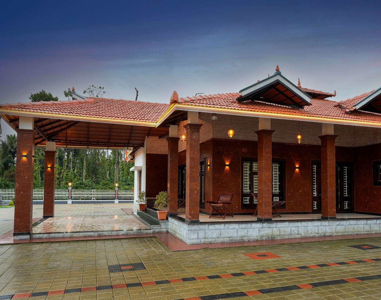 An evening shot of the main building at Bhuthanakadu Retreat, highlighting the traditional architecture and a wet, reflecting courtyard under a twilight sky.