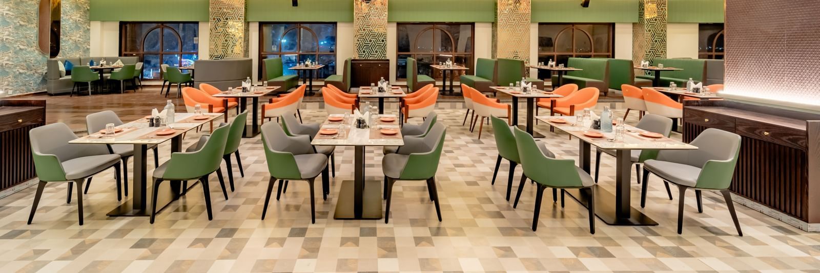 Dining area with green and orange chairs and decorative hanging lights and elements | Pravasa Hotel, Vijayapura