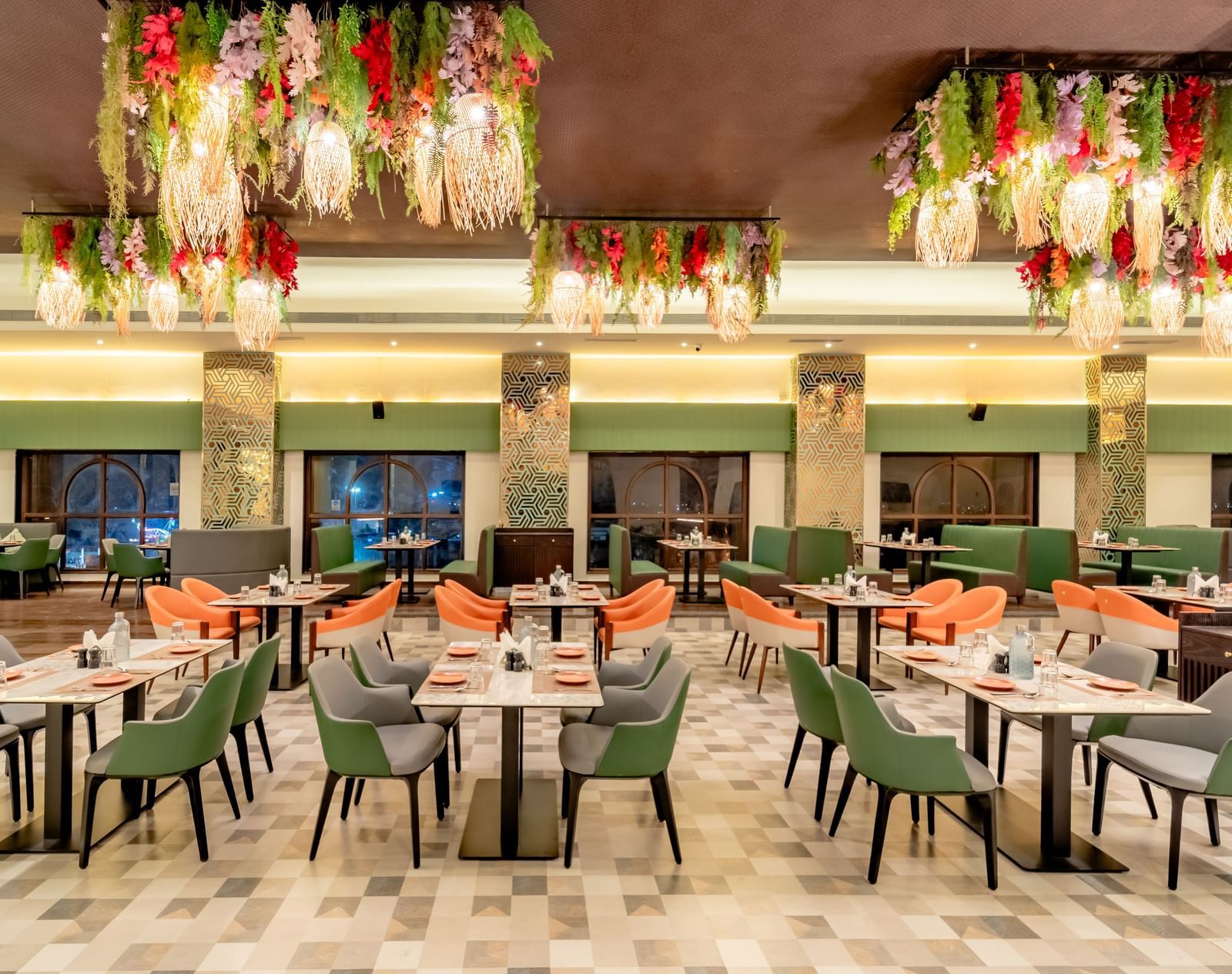 Dining area with green and orange chairs and decorative hanging lights and elements | Pravasa Hotel, Vijayapura