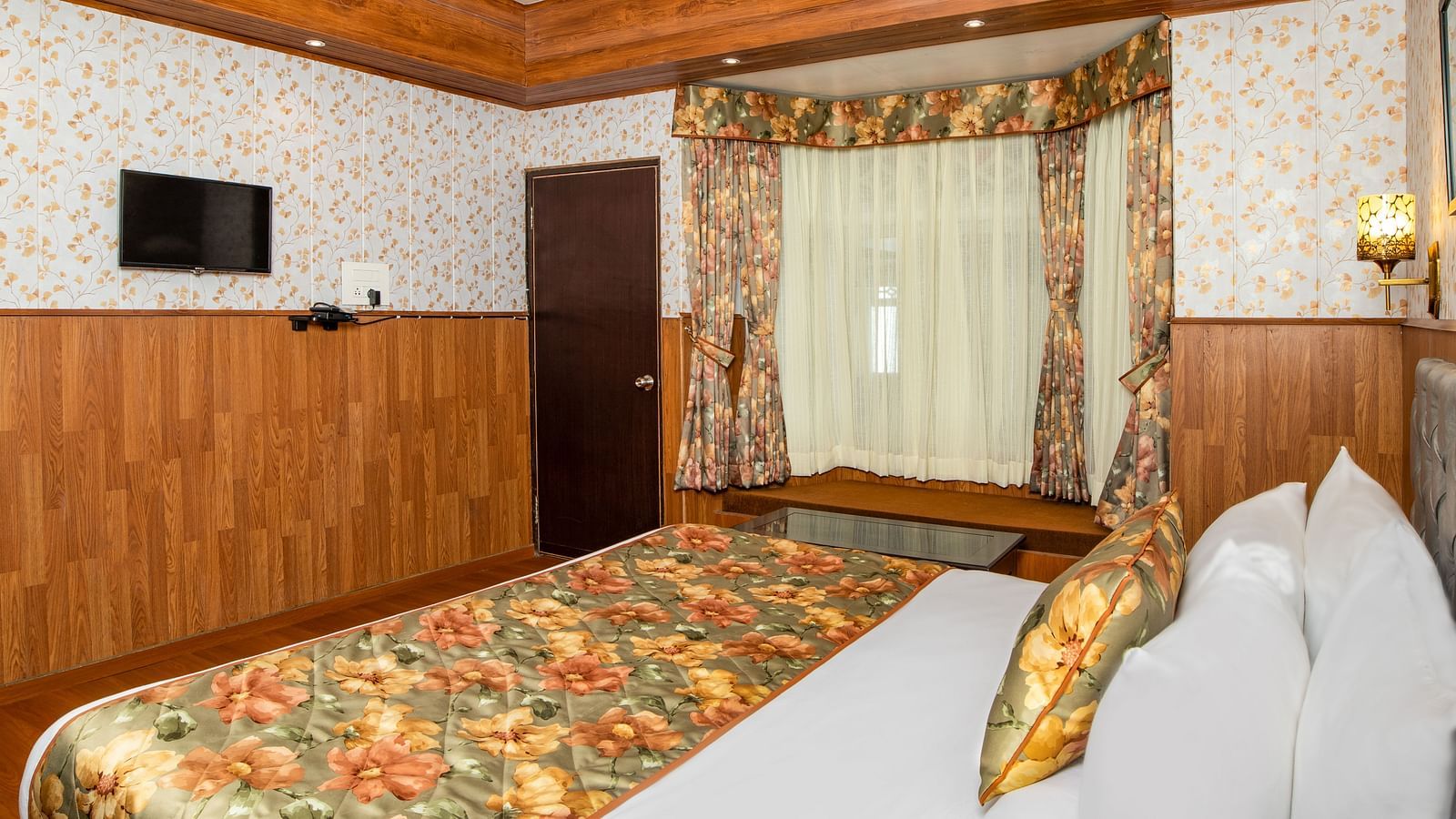A side view of a bed in a room that has a glass window and TV on the wall | Summit Oakden Resort & Spa, Mall Road