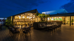 Evening view of The Residency Towers Puducherry's outdoor dining, tables set amidst lush greenery and warm lighting.