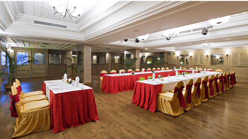 A banquet hall is set up for a celebration with tables and chairs draped in red and gold fabric - Clarks Avadh, Lucknow
