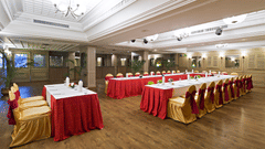 A banquet hall is set up for a celebration with tables and chairs draped in red and gold fabric - Clarks Avadh, Lucknow