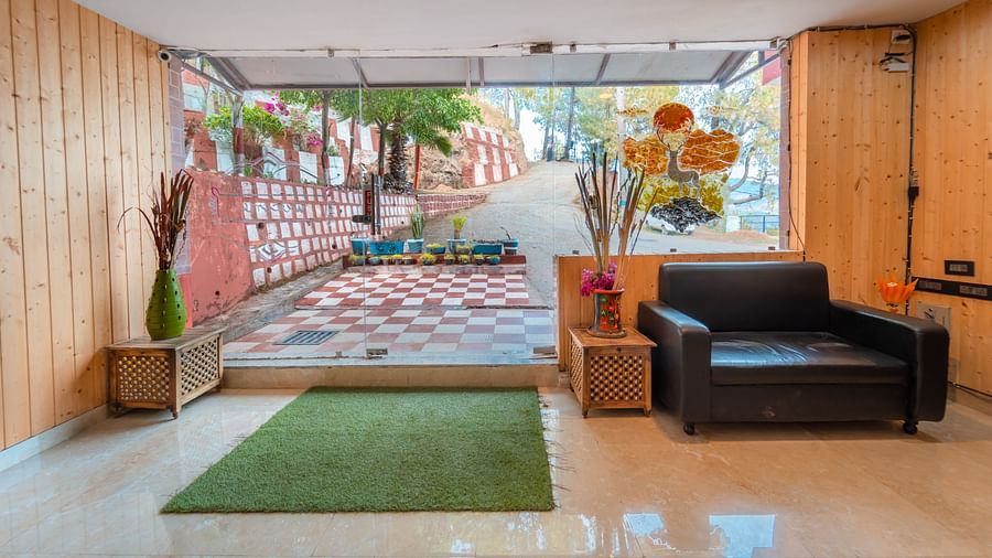 Entrance of the reception with glass doors, a sofa and flower vases at Flutter Hotels and Resorts, Lansdowne.