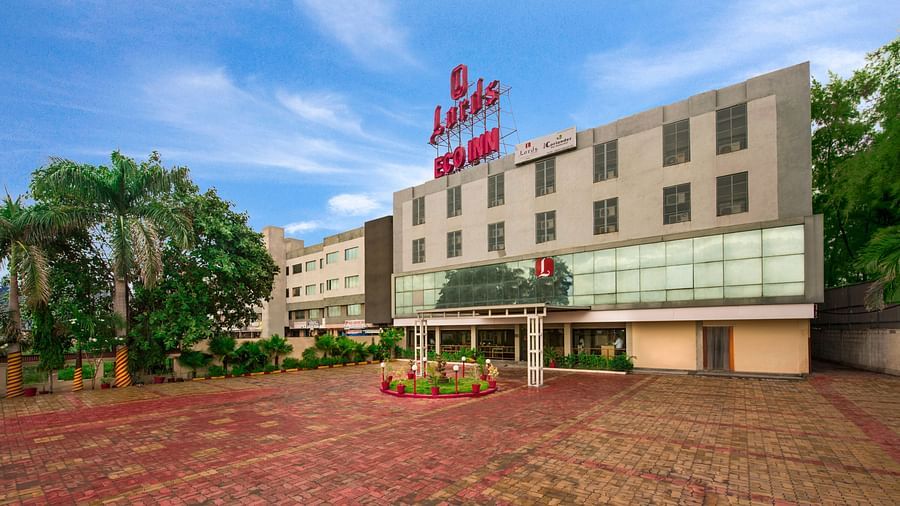 A wider exterior shot of the hotel, showing its facade and surrounding greenery - Lords Eco Inn Dahej