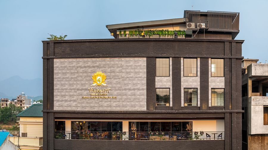 Overview shot of the facade of Vishranti Hotel Dehradun showcasing its logo engraved on the wall taken during the day.