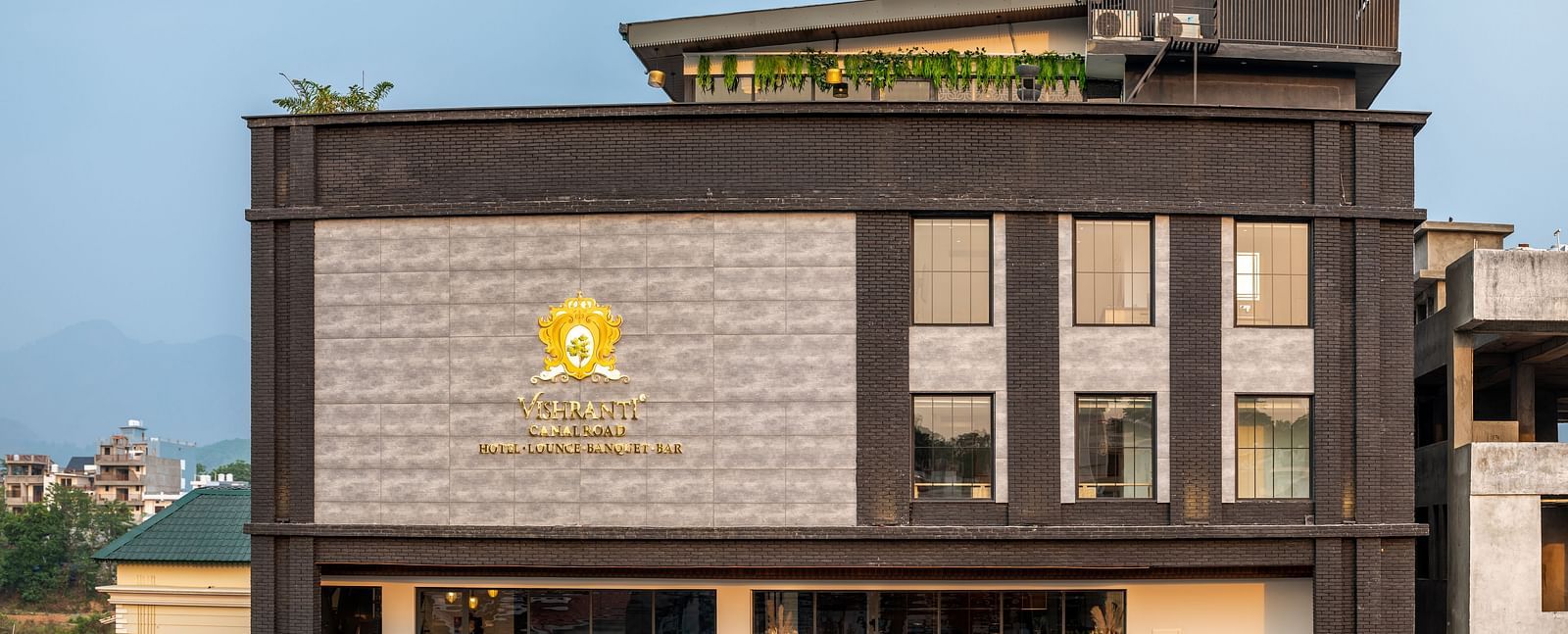 Overview shot of the facade of Vishranti- luxury boutique hotel in Dehradun showcasing its logo engraved on the wall taken during the day.