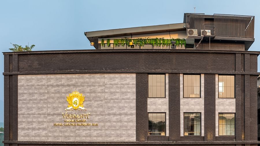 Overview shot of the facade of Vishranti Hotel Dehradun showcasing its logo engraved on the wall taken during the day.