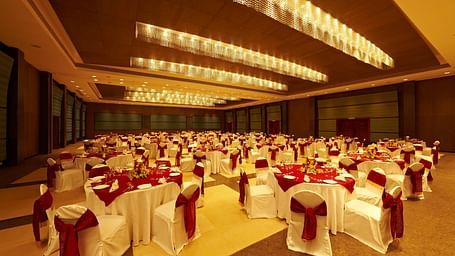 Banquet hall with tables decorated in white and red for a formal event at GRT Hotels
