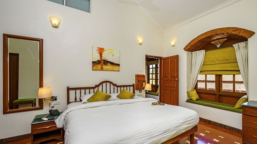 A double bed and sitting area next to the window at Babylonia - Cassis - River / Pool View room in Neemrana s Three Waters