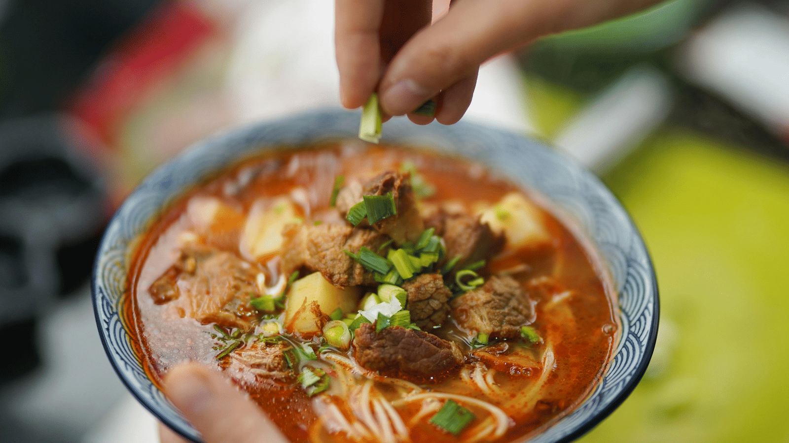 A close up shot of a bowl containing soupy Ramen garnished with chopped spring onions.