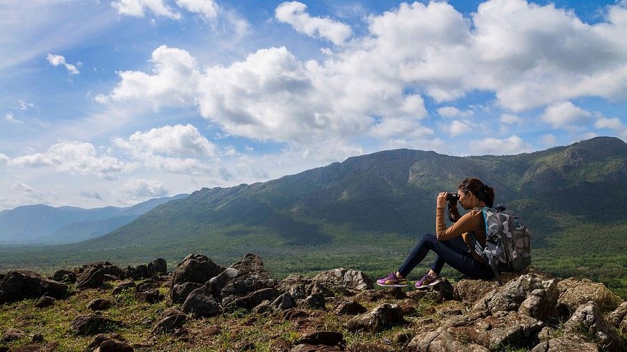 person looking through binoculars from the top of a hill 