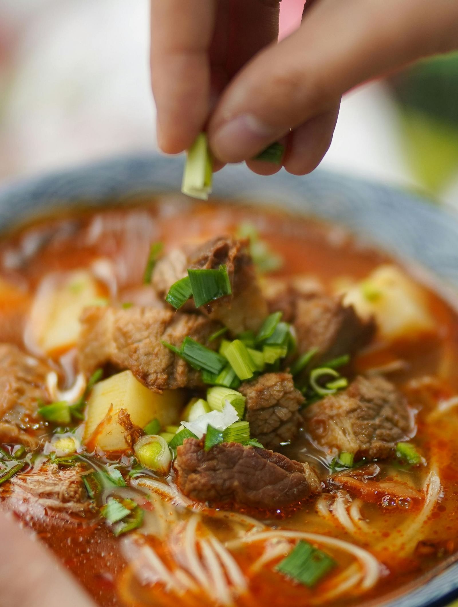 A close up shot of a bowl containing soupy Ramen garnished with chopped spring onions.