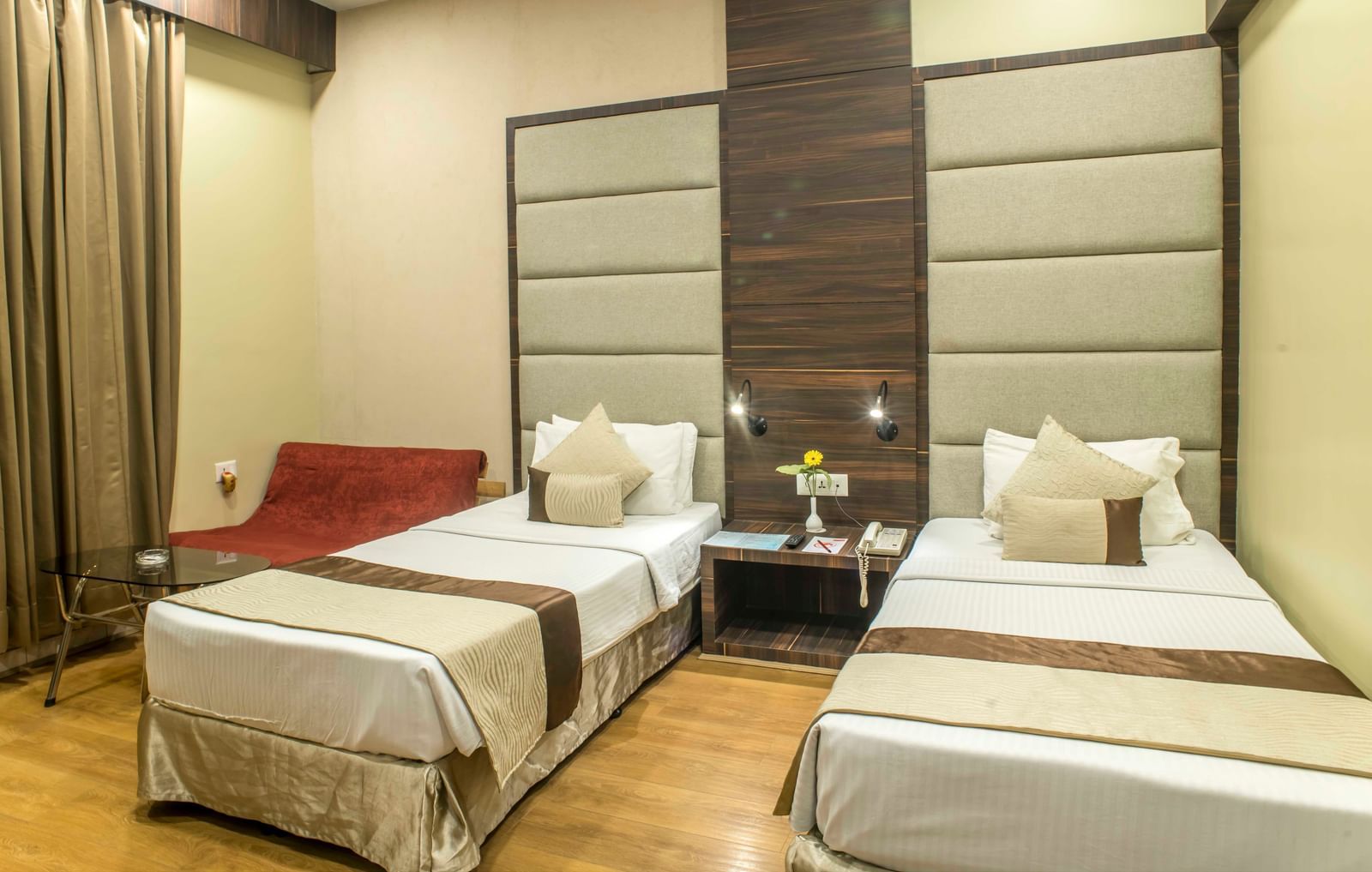 Another view of a cosy hotel room with two single beds and a red armchair| The Citi Residenci Hotel Durgapur