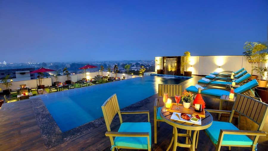 An image of a cosy dining setup near our roof top pool illuminated by warm lighting - Golden Tulip, Agra