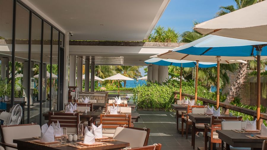 An outdoor seating at our restaurant with parasols - Alibu Resort Nha Trang
