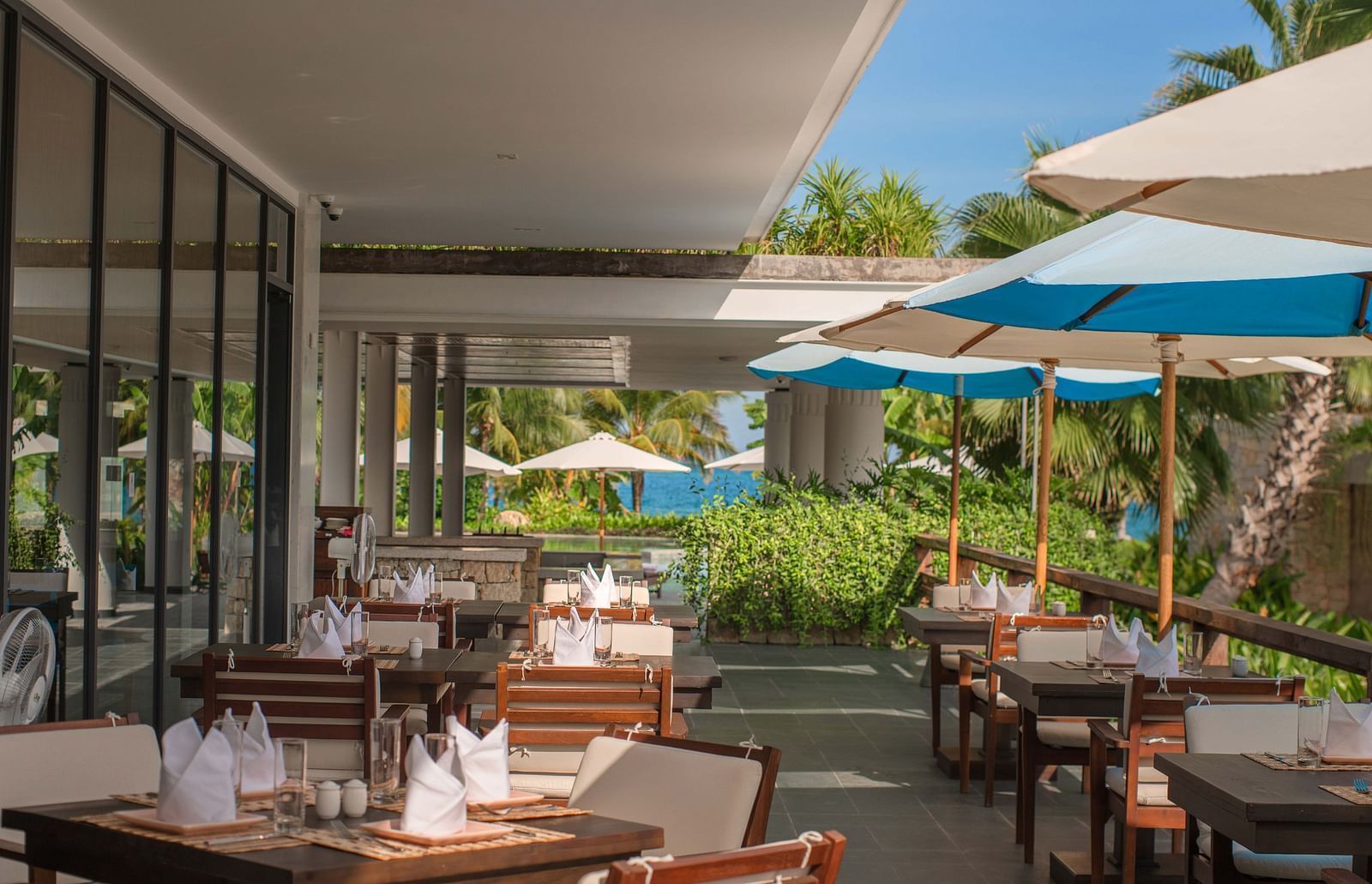 An outdoor seating at our restaurant with parasols - Alibu Resort Nha Trang