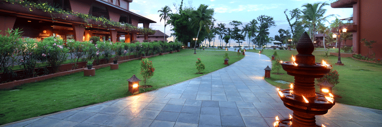 A walkway through the lawn at Uday Backwater Resort featuring diyas lit up on the side