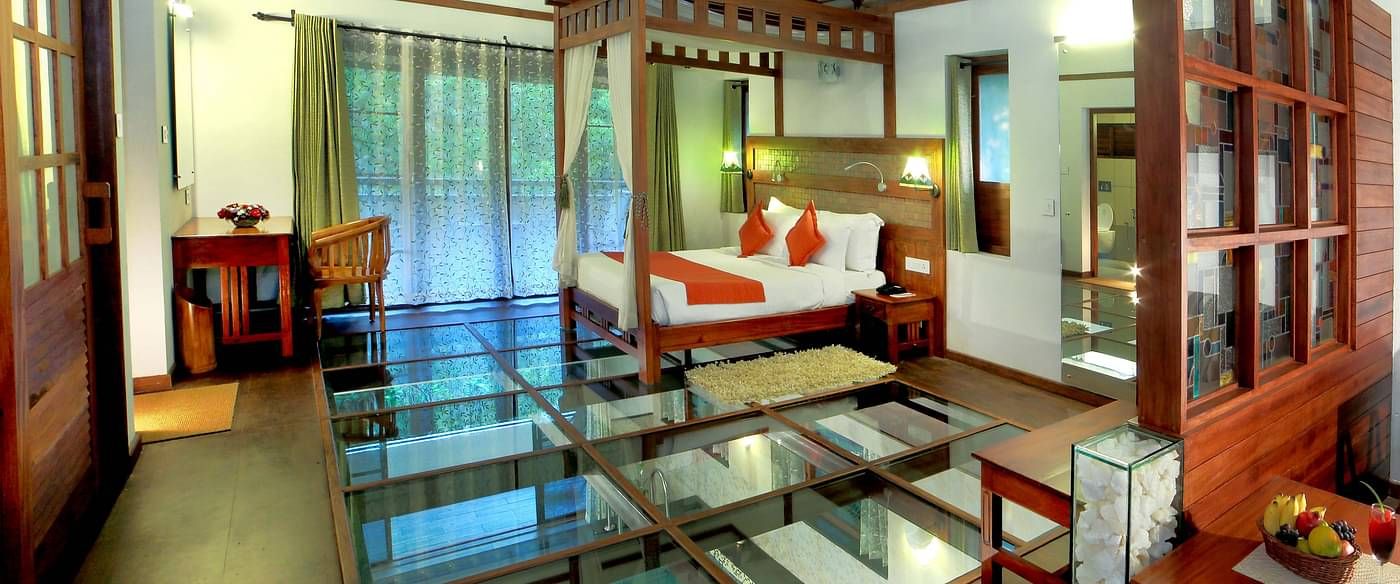 Room with a double bed and glass floor at Vythiri Resort, Wayanad