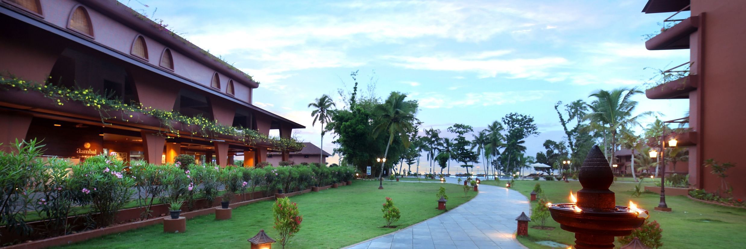 A walkway through the lawn at Uday Backwater Resort featuring diyas lit up on the side