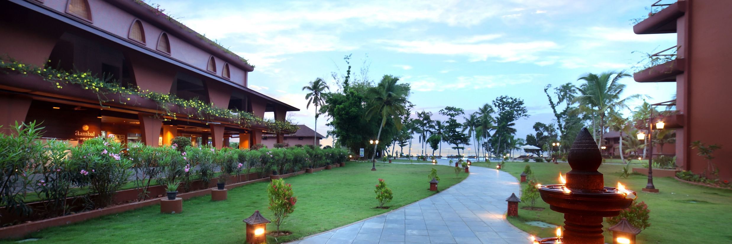 A walkway through the lawn at Uday Backwater Resort featuring diyas lit up on the side