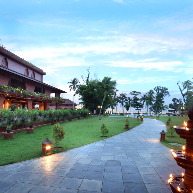 A walkway through the lawn at Uday Backwater Resort featuring diyas lit up on the side