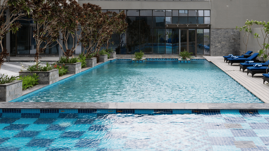 A close-up of the swimming pool with lounge seating on the sides at Merlis Hotel, Coimbatore.