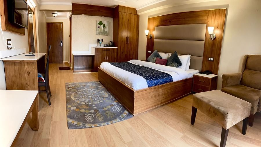 A room with a bed, chair, TV, and other amenities | Mongas Hotel & Resort, Dalhousie
