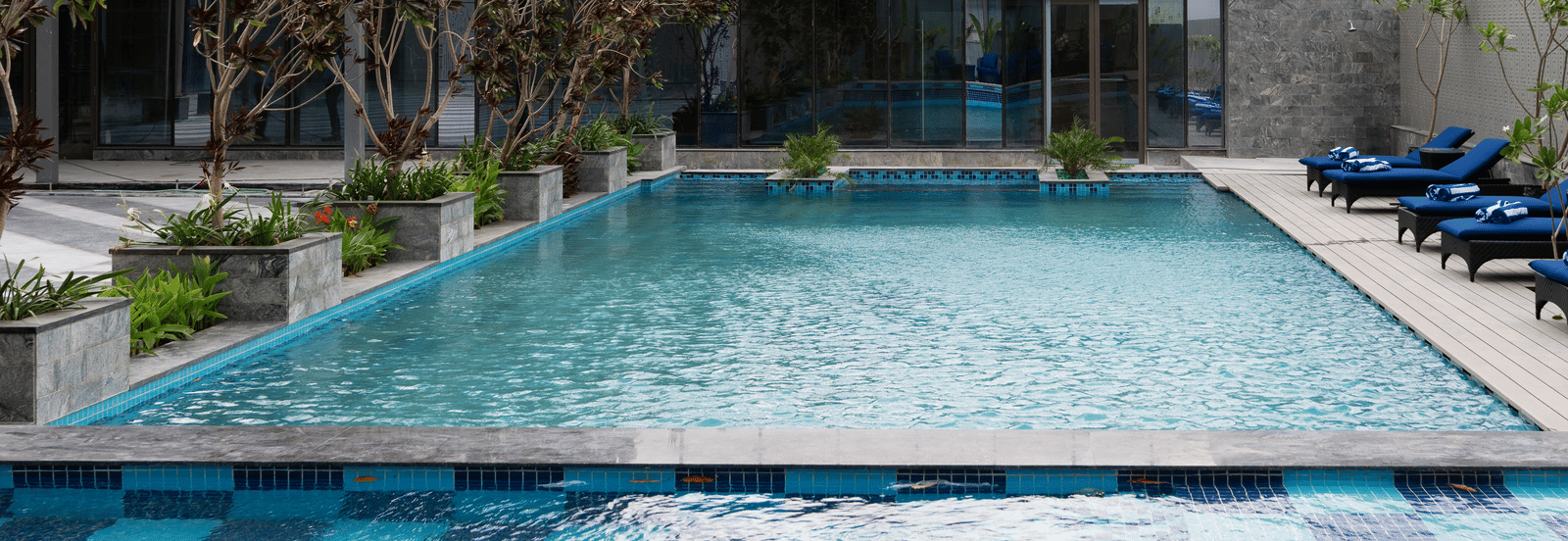 A close view of the swimming pool with lounge seating at Merlis Hotel, Coimbatore.