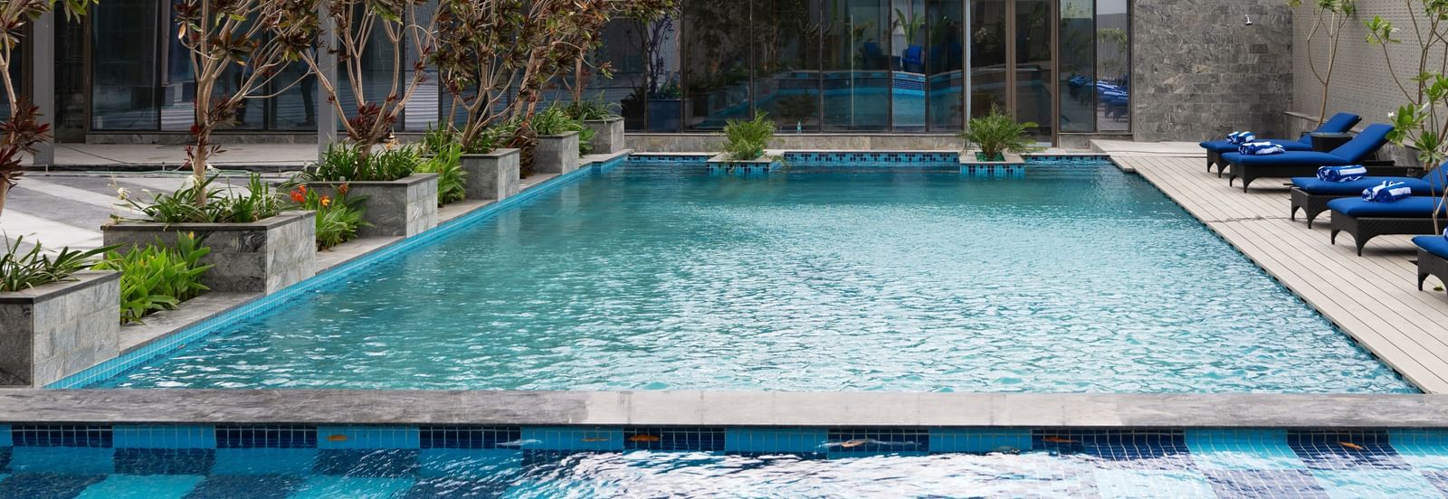 A close view of the swimming pool with lounge seating at Merlis Hotel, Coimbatore.