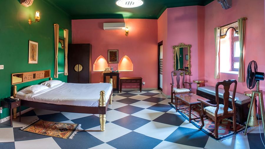 Room with bed, seating area, checkered floor, antique-style furniture, alcoves, framed artwork, and a fan - Tijara Fort-Palace - 19th Century, Alwar.