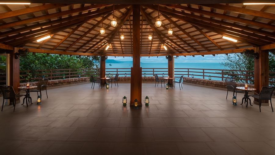 A wide angle shot of a gazebo with teracotta tiles, tables, chairs and candles - Highland Sarovar Portico, Sindhudurg