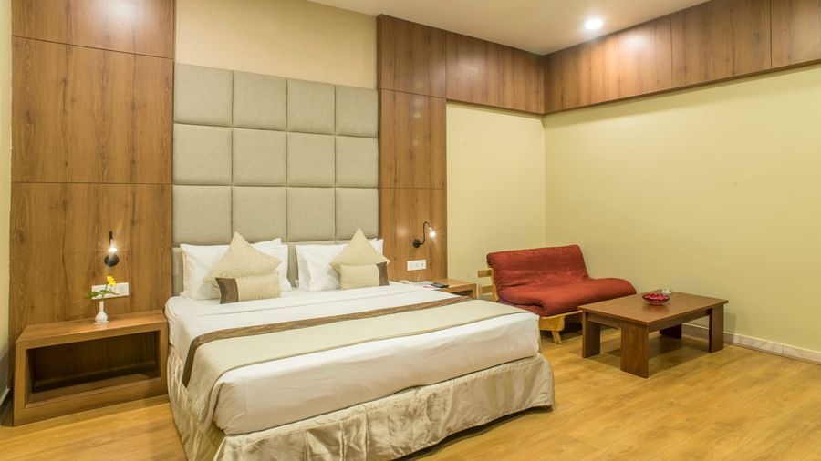 Inviting hotel room with a king size bed, a red armchair, and soft lighting at The Citi Residenci Hotel Durgapur