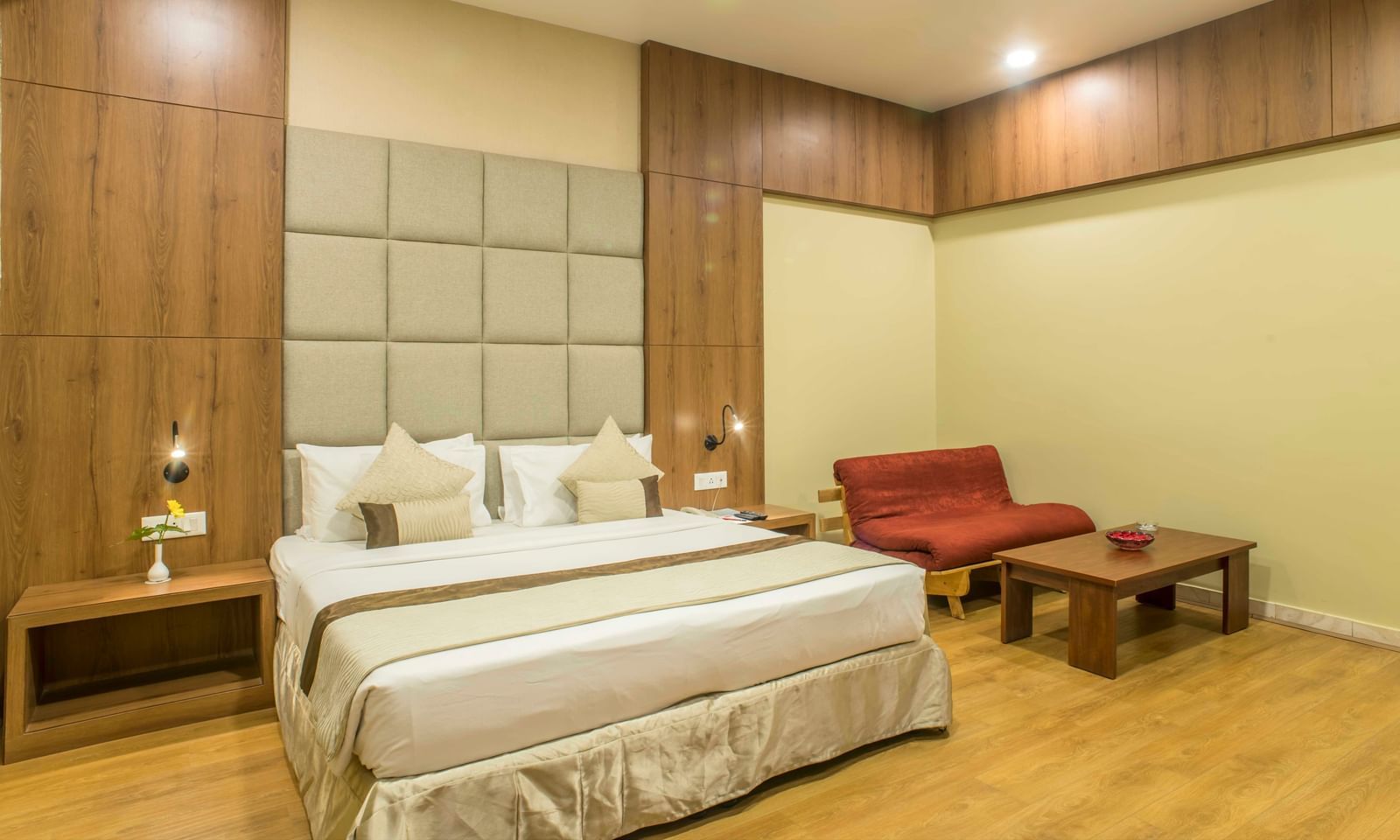 Inviting hotel room with a king size bed, a red armchair, and soft lighting at The Citi Residenci Hotel Durgapur
