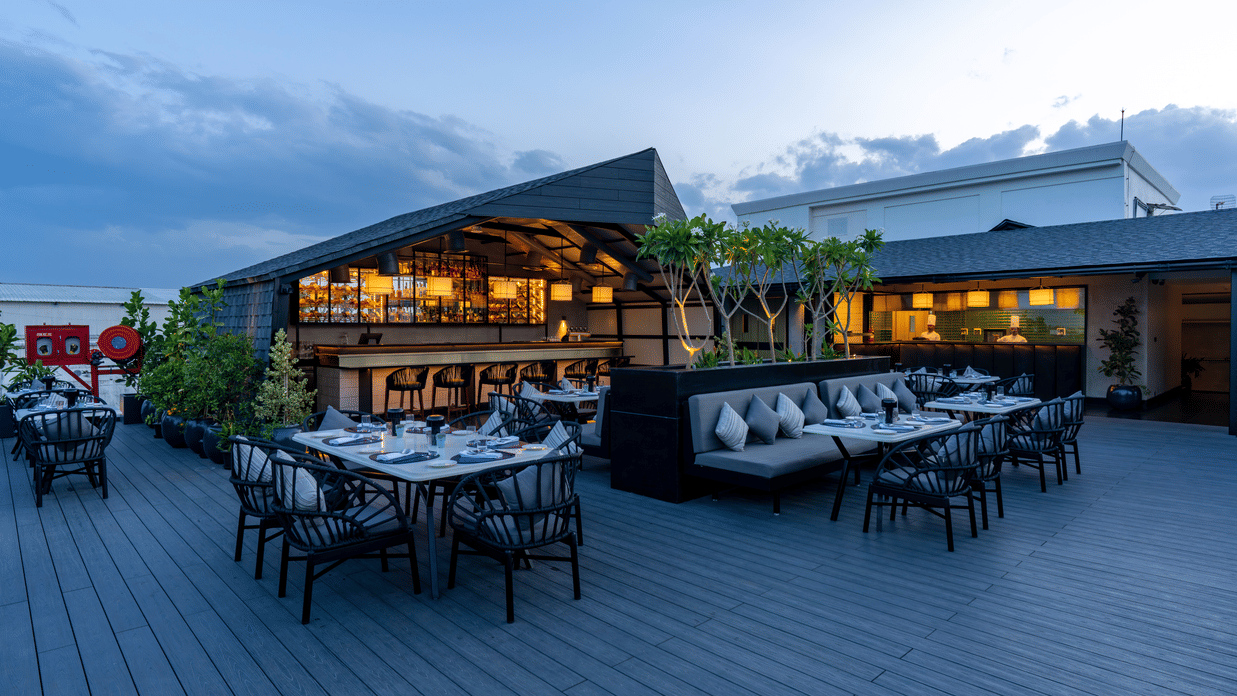 Expansive view of The Residency Towers Puducherry's elegant rooftop dining, showcasing tables and the serene sky.