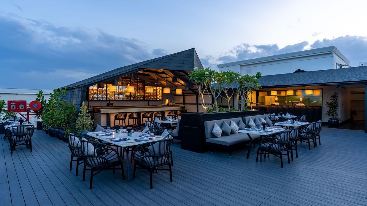 Expansive view of The Residency Towers Puducherry's elegant rooftop dining, showcasing tables and the serene sky.