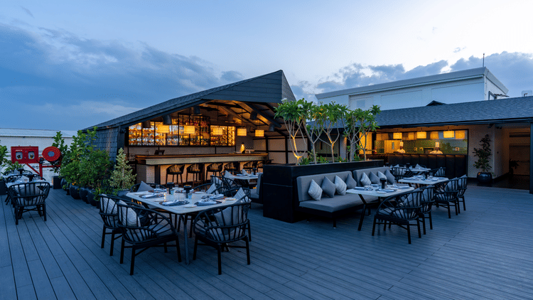 Expansive view of The Residency Towers Puducherry's elegant rooftop dining, showcasing tables and the serene sky.