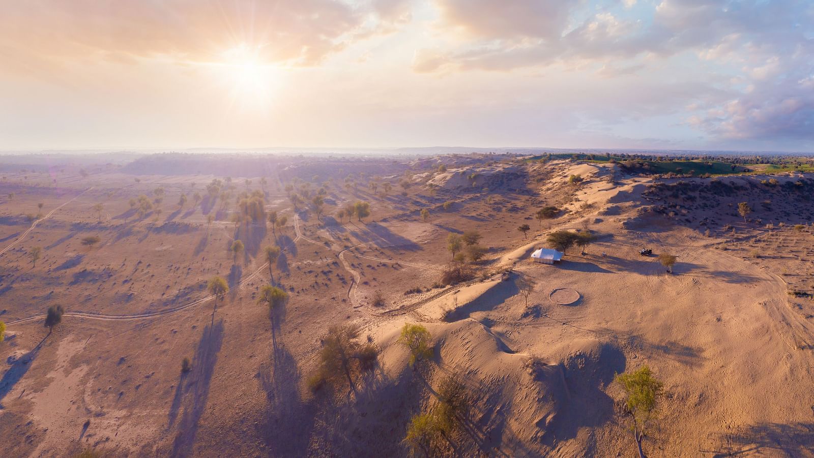 The campsite is seen from a higher altitude, showing the isolated and tranquil setting among the gentle desert terrain - MANVAR Resort & Desert Camp