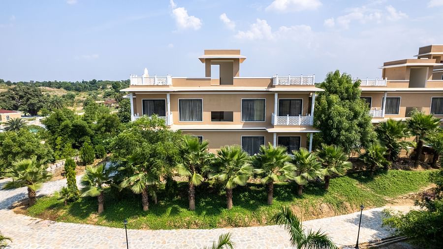A straight-on view of a building with a green lawn in the foreground - Rajbagh Wellness, Udaipur